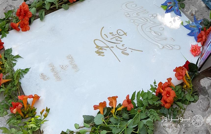 سنگ مزار «محمدرضا شجریان» در آرامگاه فردوسی؛ سنگی سفید که با دورتادورش گل‌های طبیعی گذاشته شده‌است.